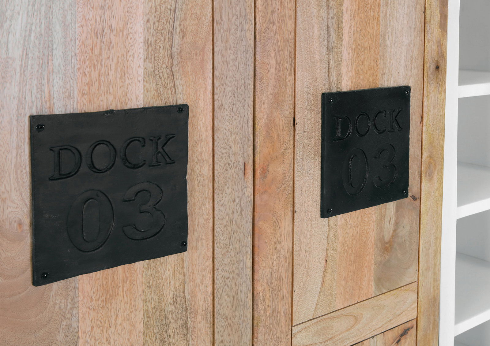 Nahaufnahme eines Highboards aus Holz mit schwarzen Metallplatten, die mit 'DOCK 03' beschriftet sind. Perspektive von vorne.
