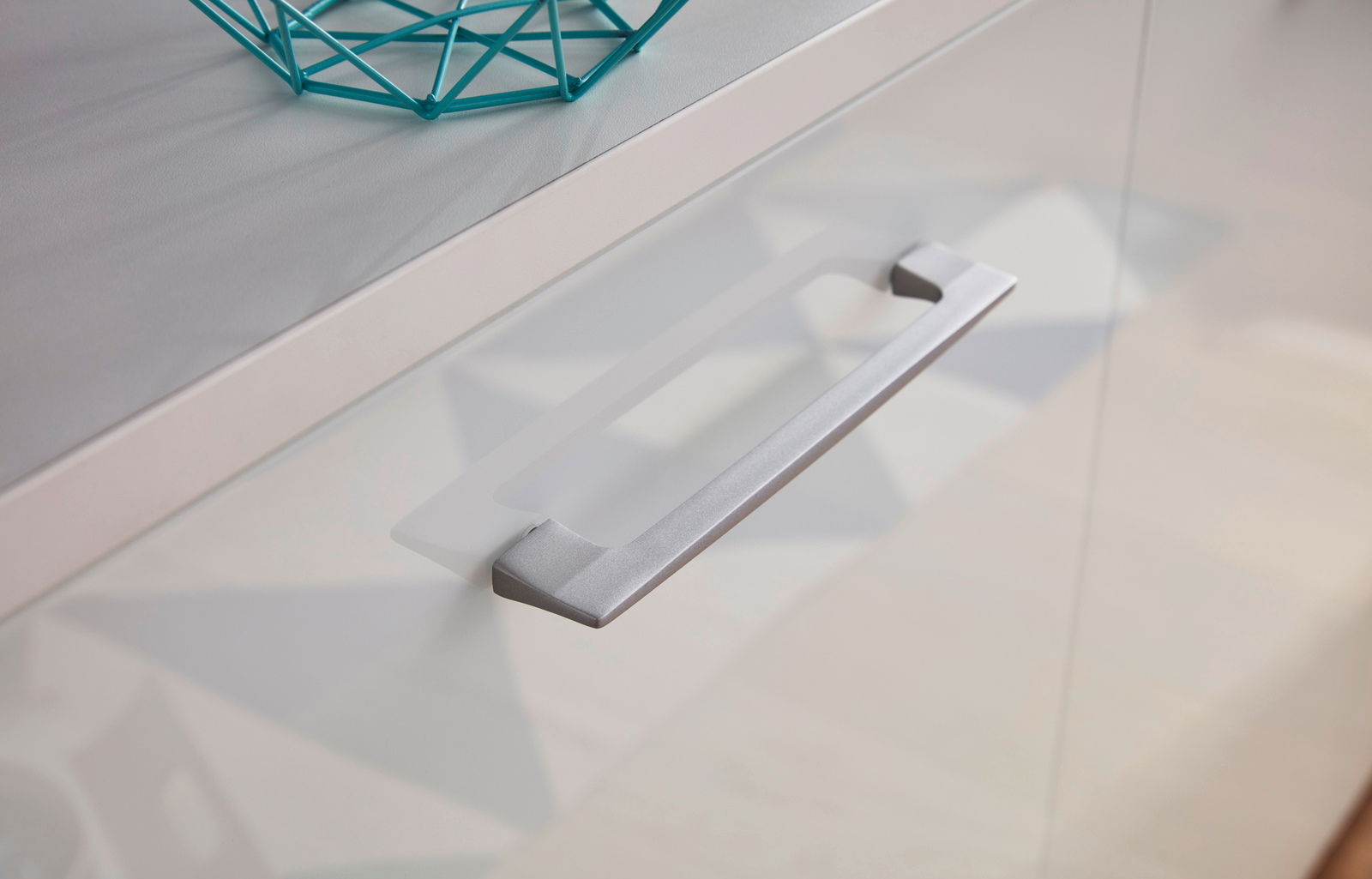 Nahaufnahme eines modernen Sideboards mit silbernem Griff und dekorativem Element, seitliche Perspektive