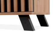 Nahaufnahme eines Sideboards mit Holzlamellen und schrägen schwarzen Metallbeinen, seitliche Perspektive.