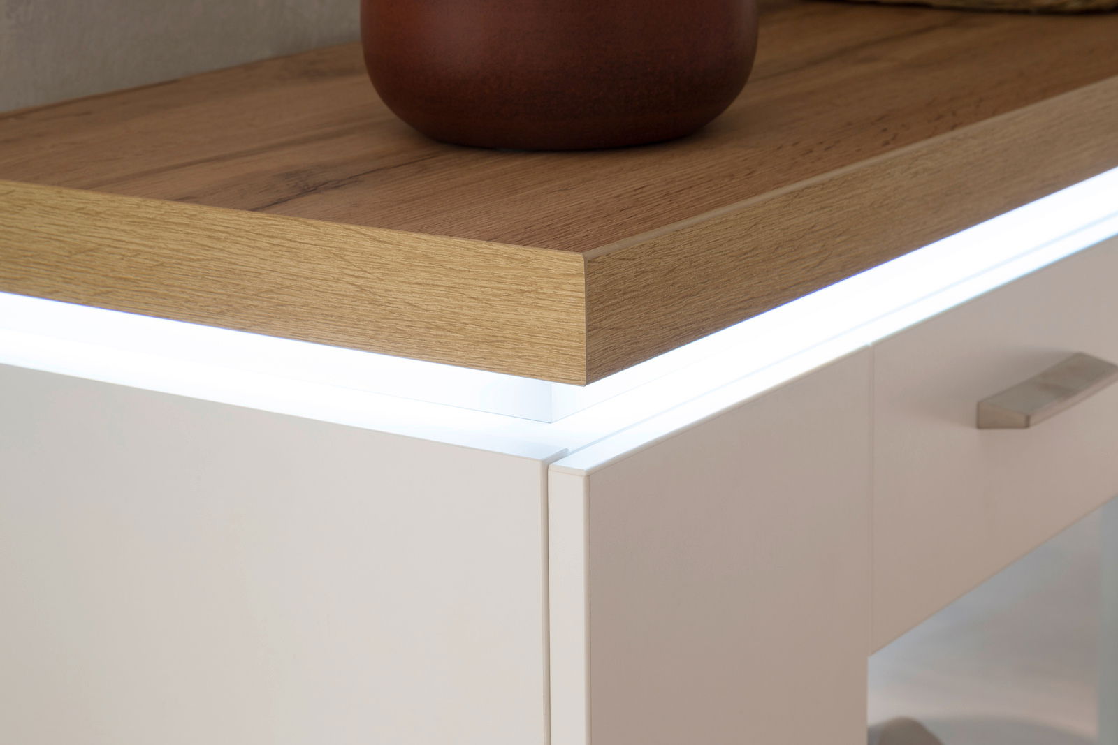 Nahaufnahme eines modernen Sideboards mit Holzoberfläche und integrierter LED-Beleuchtung, seitliche Perspektive.