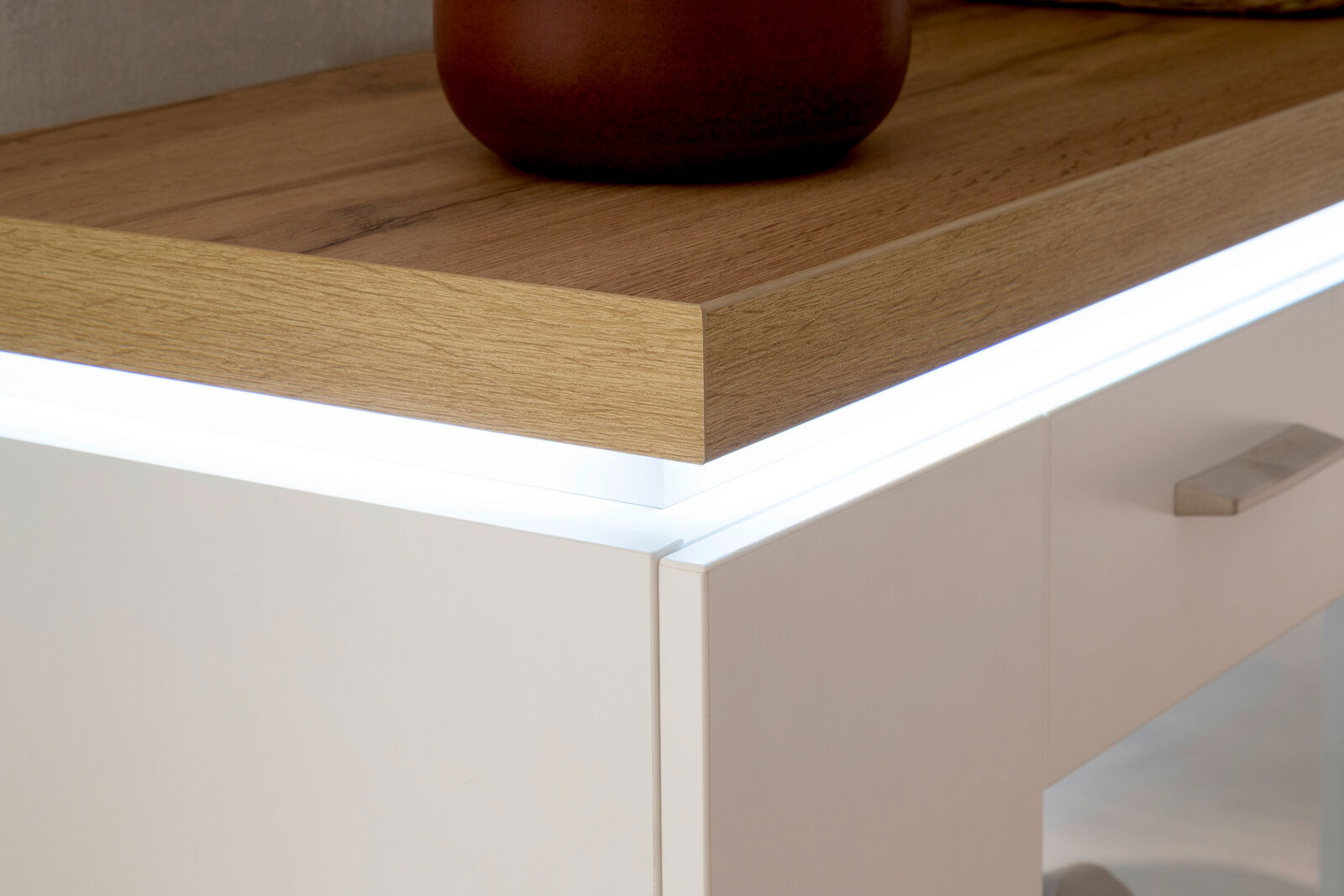 Nahaufnahme eines modernen Sideboards mit Holzoberfläche und integrierter LED-Beleuchtung, seitliche Perspektive.