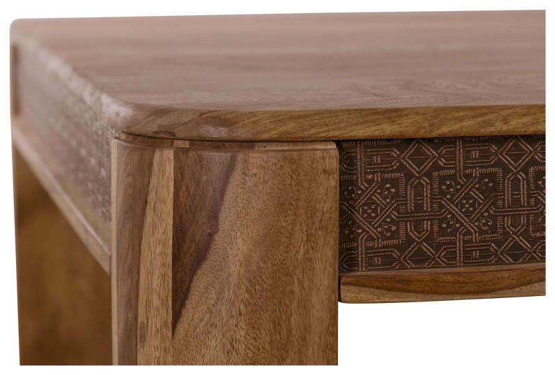 Nahaufnahme einer Ecke eines Esstisches aus Holz mit dekorativen Schnitzereien an der Seite, Perspektive von schräg oben.