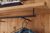 Nahaufnahme eines Holzregals mit schwarzer Kleiderstange und Kleiderbügeln, Perspektive von unten.
