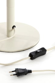 Nahaufnahme eines Lampenfußes mit rundem Sockel, Kabel und Schalter, seitliche Perspektive.