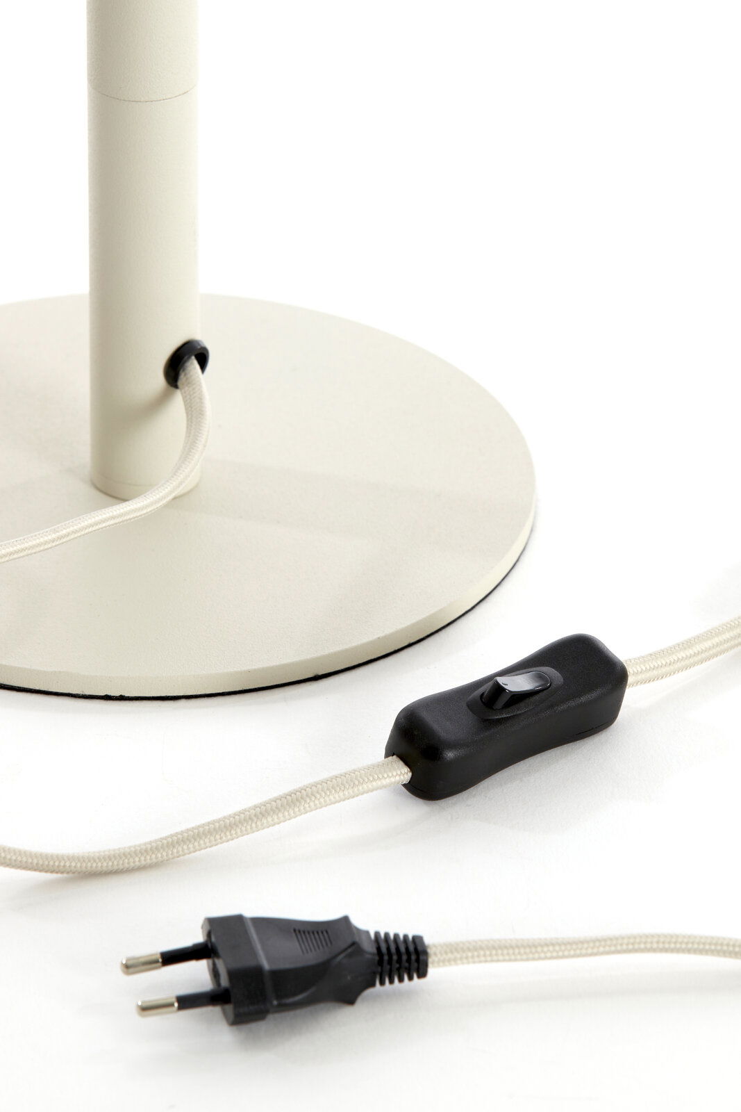 Nahaufnahme eines Lampenfußes mit rundem Sockel, Kabel und Schalter, seitliche Perspektive.