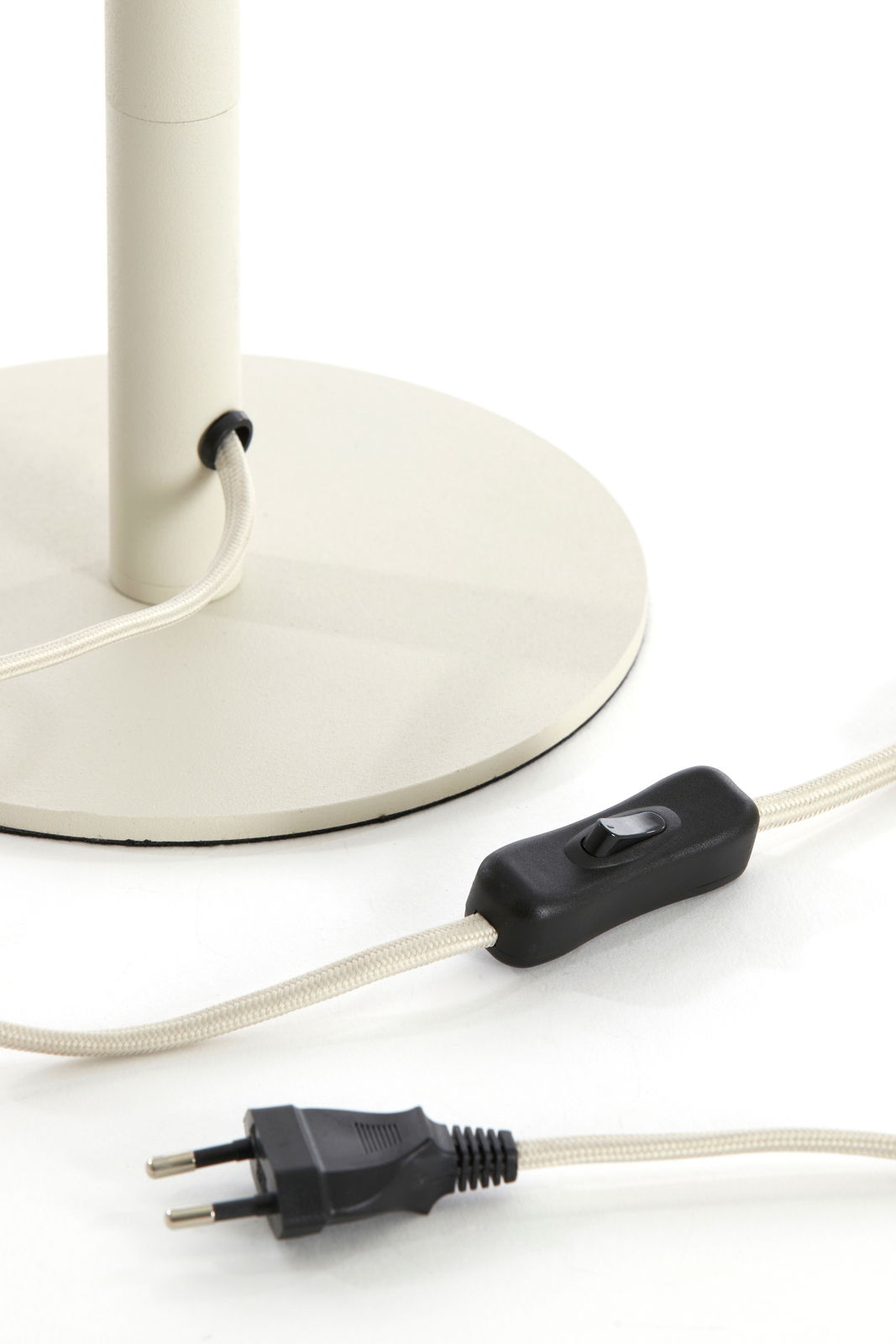 Nahaufnahme eines Lampenfußes mit rundem Sockel, Kabel und Schalter, seitliche Perspektive.