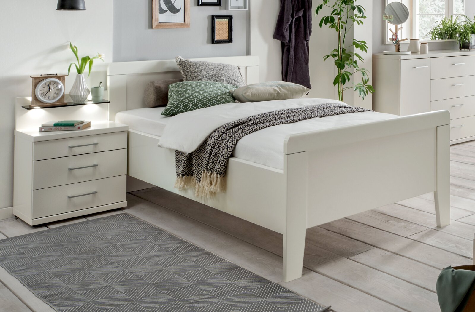 Weißes Bettgestell in einem modernen Schlafzimmer, seitliche Perspektive