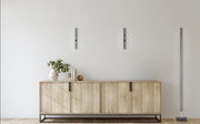 Moderne LED-Stehleuchte BEN in einem eleganten, minimalistischen Design, stehend neben einem Holzschrank in einem hellen Raum. Die Perspektive zeigt die Leuchte von vorne.