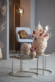 Zwei runde Couchtische mit Glasplatte und goldfarbenem Gestell, dekoriert mit strukturierten Vasen und Trockenblumen, in einem modernen Wohnzimmer mit seitlicher Perspektive.