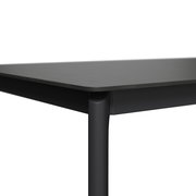 Nahaufnahme eines modernen, schwarzen Gartentisches mit abgerundeten Ecken und schlanken Beinen, seitliche Perspektive.