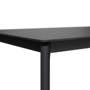 Nahaufnahme eines modernen, schwarzen Gartentisches mit abgerundeten Ecken und schlanken Beinen, seitliche Perspektive.