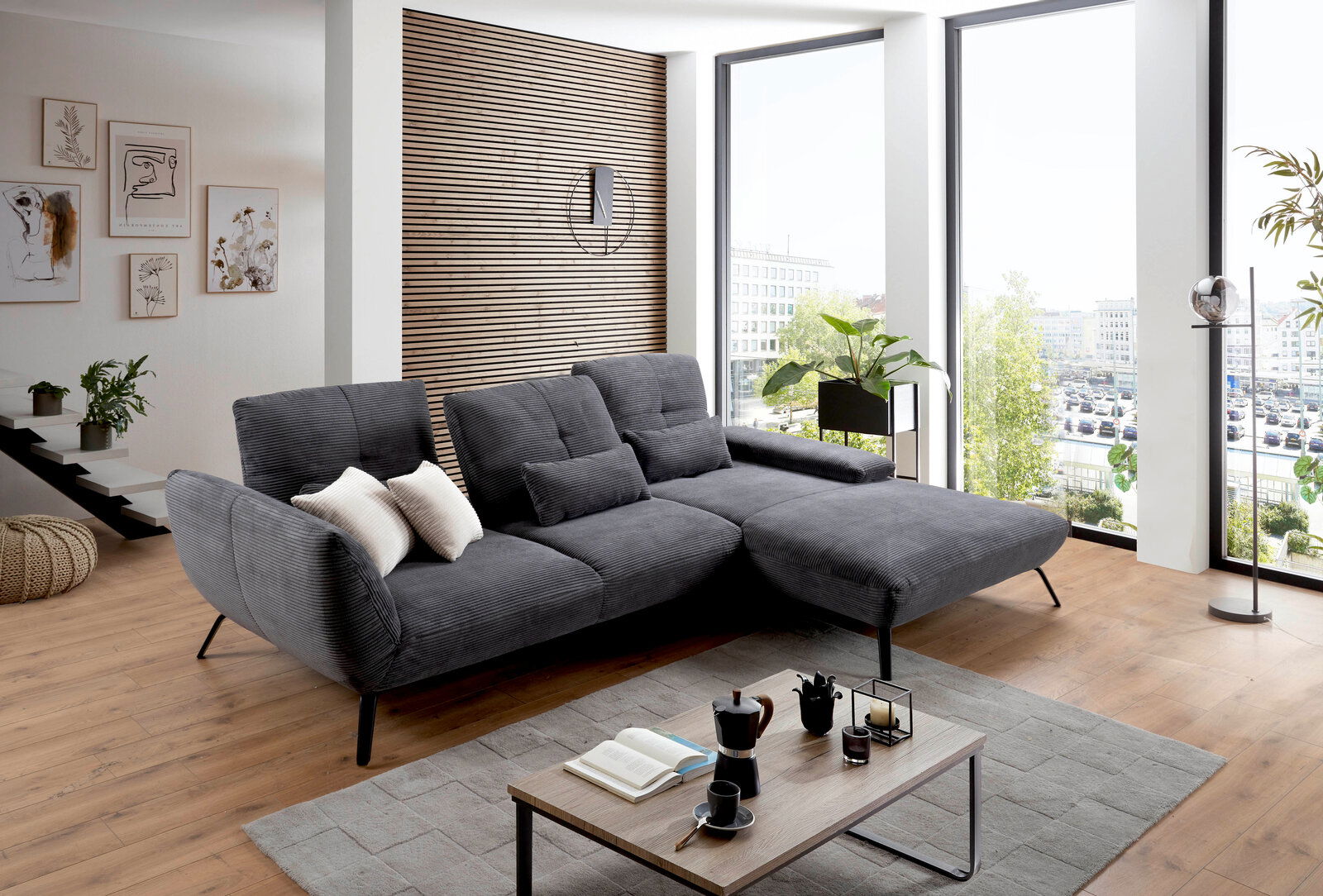 Graue Rundecke in modernem Wohnzimmer mit großen Fenstern, von vorne betrachtet.