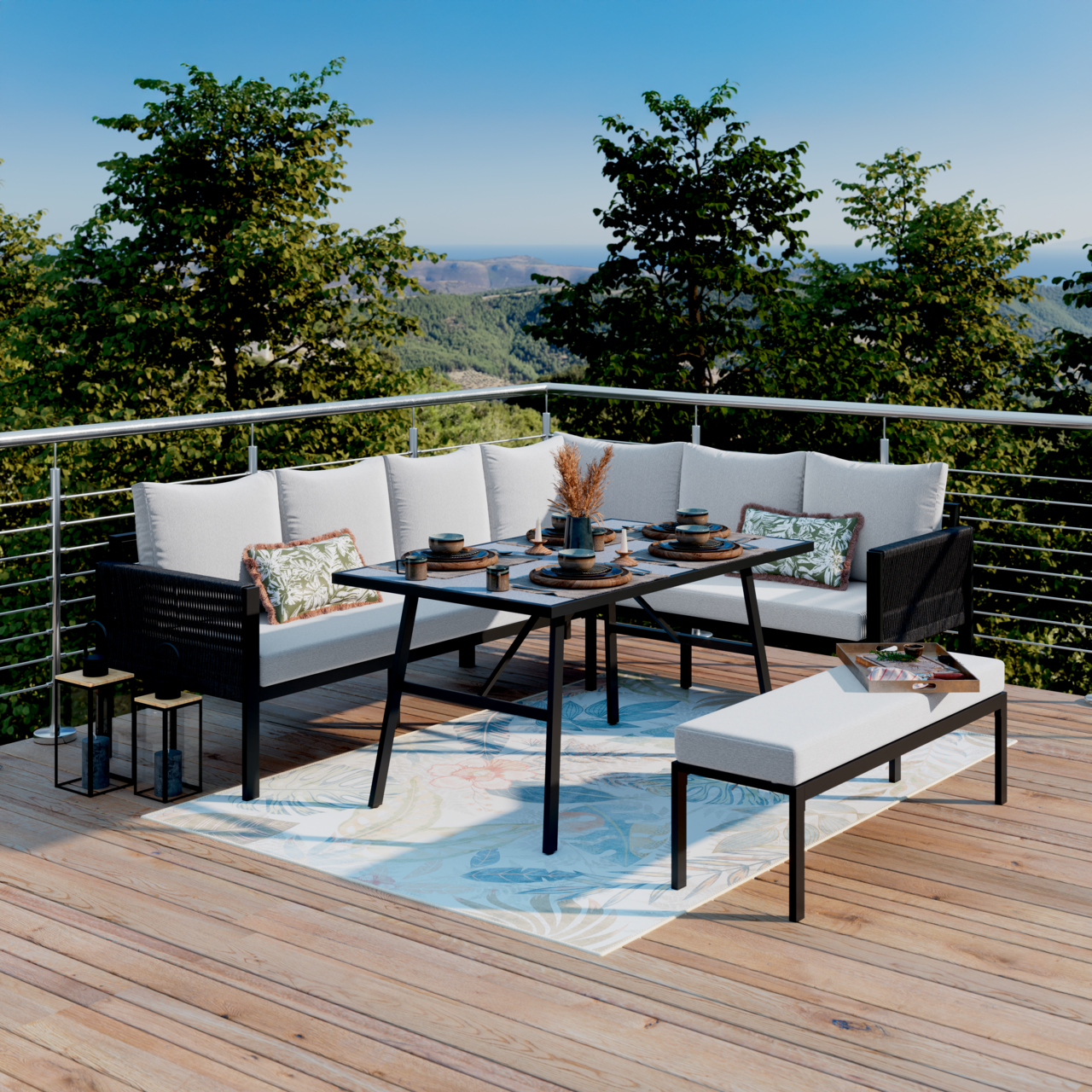 Moderne Outdoor-Lounge-Essgruppe auf Holzterrasse: L-förmiges Sofa mit hellen Polstern, schwarzer Esstisch und Bank auf gemustertem Teppich, mit gedecktem Tisch und Bergblick im Hintergrund, Perspektive frontal leicht erhöht.