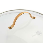 Nahaufnahme eines Topfdeckels mit goldenem Griff und Glasoberfläche, seitliche Perspektive.