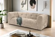 Beiges, gepolstertes 3-Sitzer-Sofa mit Kassettensteppung in modernem Wohnzimmer, schräg von vorne aus leicht erhöhter Perspektive fotografiert.