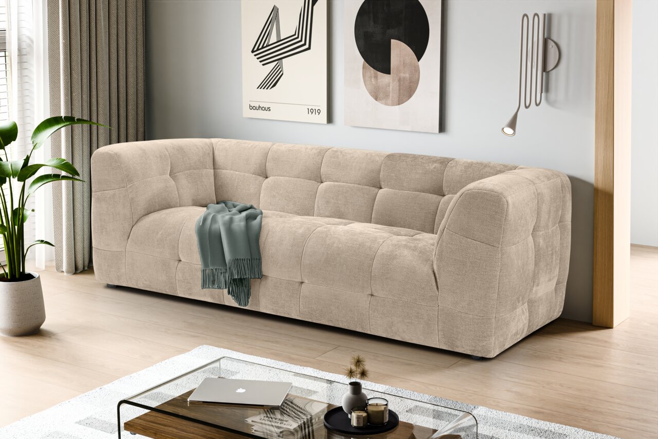 MID.YOU Sofa 2,5 Sitzer TENSO Beiges, gepolstertes 3-Sitzer-Sofa mit Kassettensteppung in modernem Wohnzimmer, schräg von vorne aus leicht erhöhter Perspektive fotografiert.
