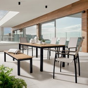 Moderne tuintafel met houten blad en metalen onderstel op een terras, omringd door stoelen en een bank, zijaanzicht.