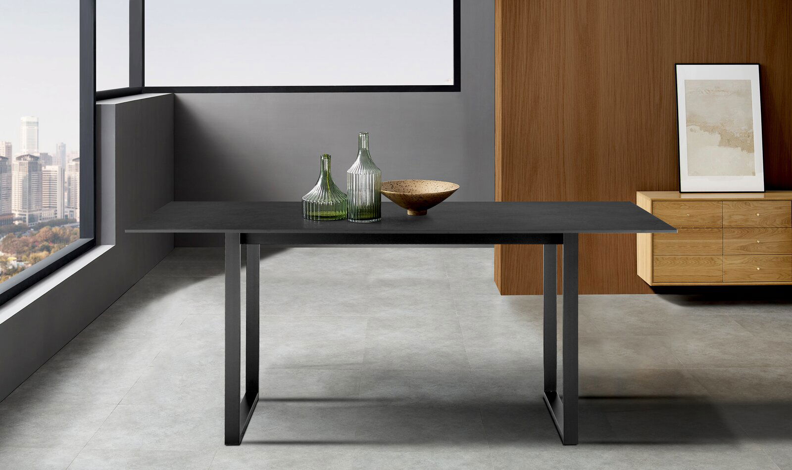Z2 Esstisch PER Moderner Esstisch mit schwarzer Tischplatte und Metallbeinen, dekoriert mit grünen Glasflaschen und einer Schale, in einem stilvollen Raum mit Stadtblick, aus frontaler Perspektive.