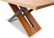 Nahaufnahme eines modernen Esstisches mit einer Tischplatte aus Holz und einem X-förmigen Metallgestell, seitliche Perspektive.