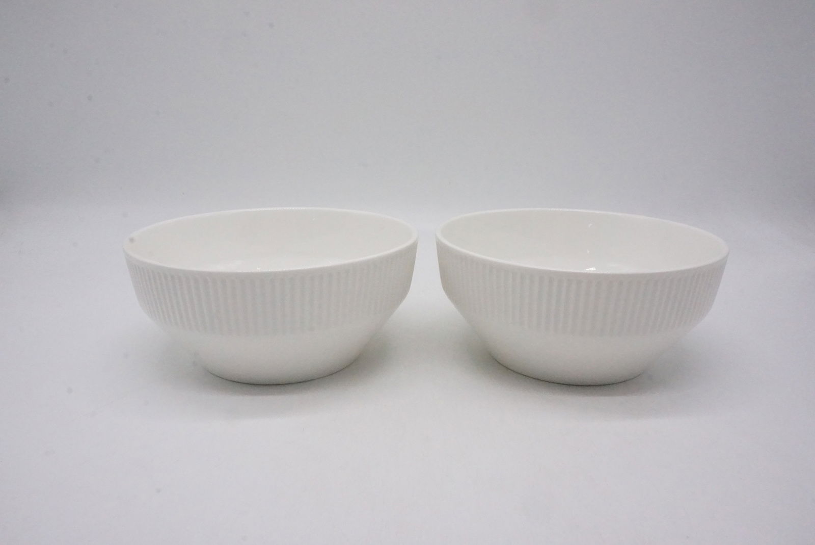 Zwei weiße Schüsseln mit geriffelter Oberfläche, frontal fotografiert auf weißem Hintergrund.