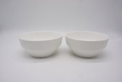Twee witte schalen met een geribbeld oppervlak, van voren gefotografeerd tegen een witte achtergrond.