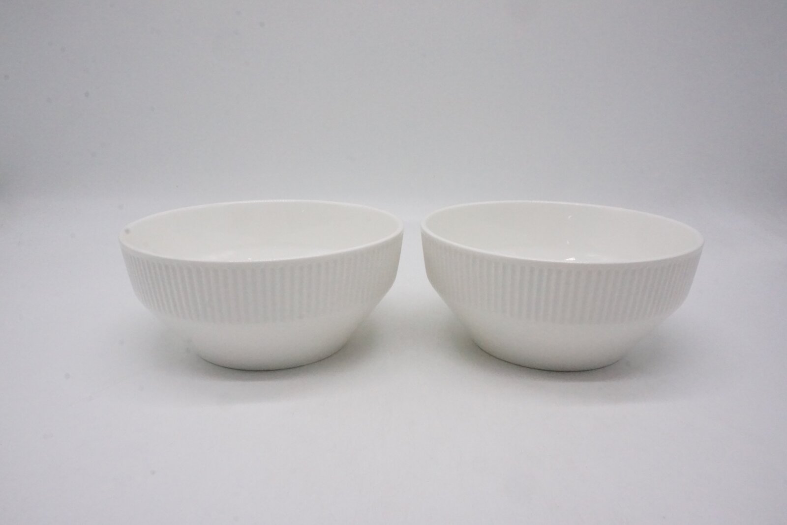 Twee witte schalen met een geribbeld oppervlak, van voren gefotografeerd tegen een witte achtergrond.