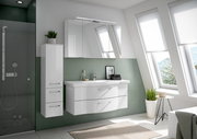 Moderner Badblock in einem hellen Badezimmer mit schrägen Fenstern, bestehend aus einem weißen Waschtisch mit zwei Schubladen und einem hohen Schrank, seitliche Perspektive.