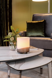 Elegante Vase auf einem Marmortisch, umgeben von einem stilvollen Wohnzimmer mit einem Sessel im Hintergrund, seitliche Perspektive.
