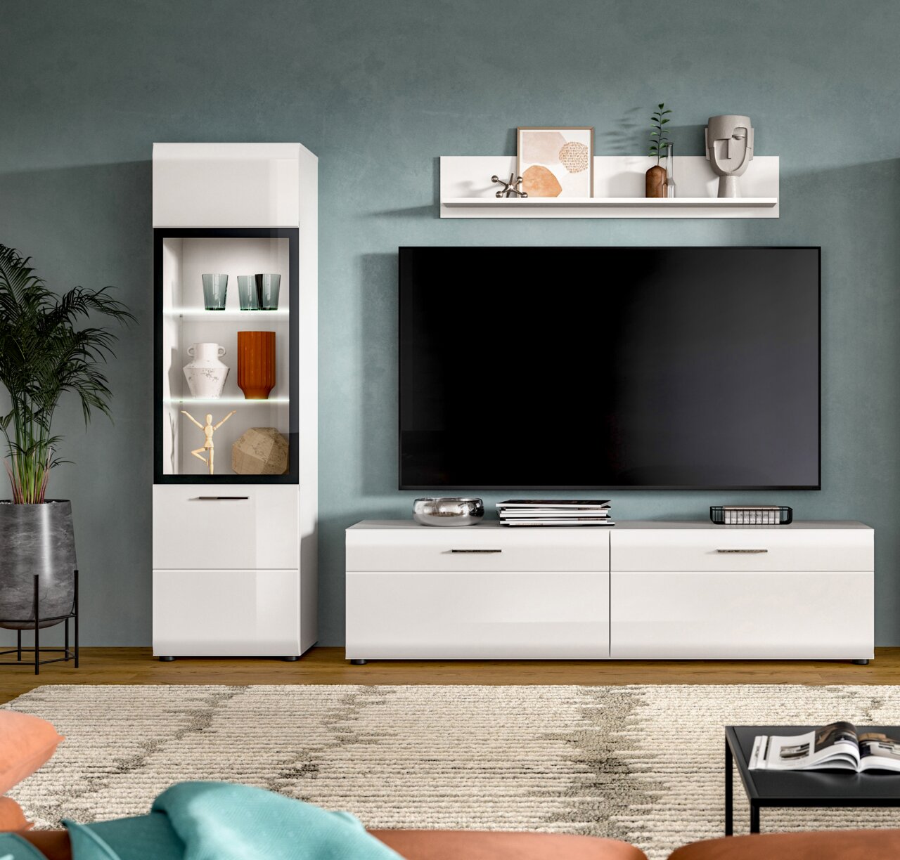 Modernes Wohnzimmer-Entertainment-Set in Weiß mit TV-Lowboard und Vitrine, großer Flachbildfernseher an der Wand, Wandregal mit Deko Frontalansicht auf die Möbel.