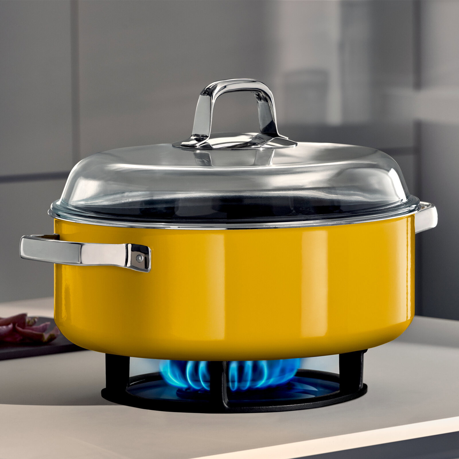 WMF Schmortopf mit Deckel FUSIONTEC MINERAL PRO Gelber Schmortopf mit Deckel auf einem Gasherd, seitliche Perspektive