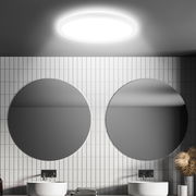 Runde LED-Deckenleuchte mit Bewegungssensor, von unten betrachtet, in einem modernen Badezimmer mit zwei runden Spiegeln und weißen Fliesen.