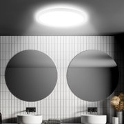 Ronde led-plafondlamp met bewegingssensor, gezien van onderaf, in een moderne badkamer met twee ronde spiegels en witte tegels.