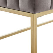 Nahaufnahme einer Hockerbank mit grauem Polster und goldfarbenem Metallrahmen, seitliche Perspektive