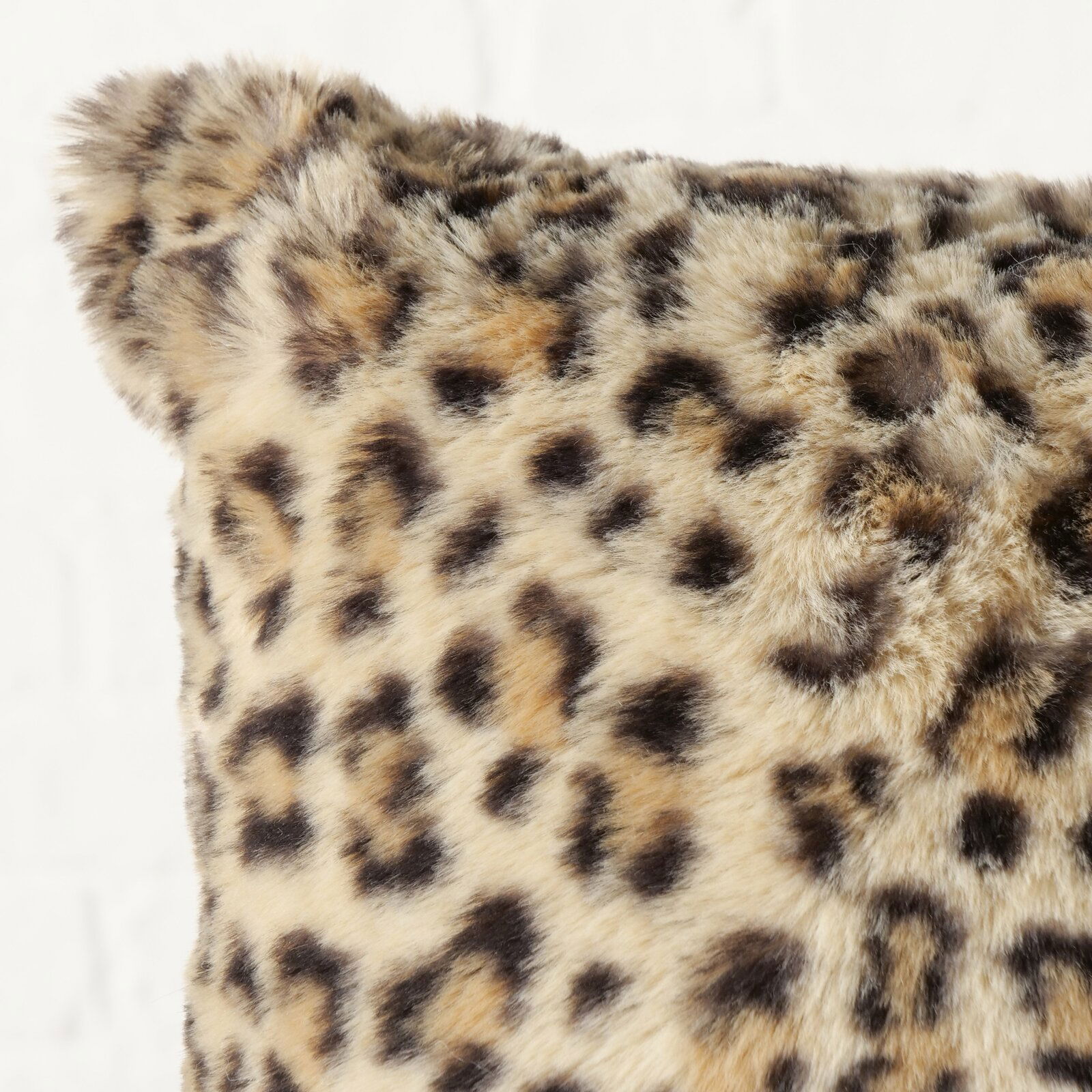 Boltze Kissen Leony AFRIKA Nahaufnahme eines weichen Kissens mit Leopardenmuster, perspektivisch von der Seite fotografiert.