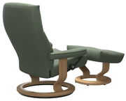 Grüner Einzelsessel mit passendem Hocker, seitliche Perspektive, Holzgestell