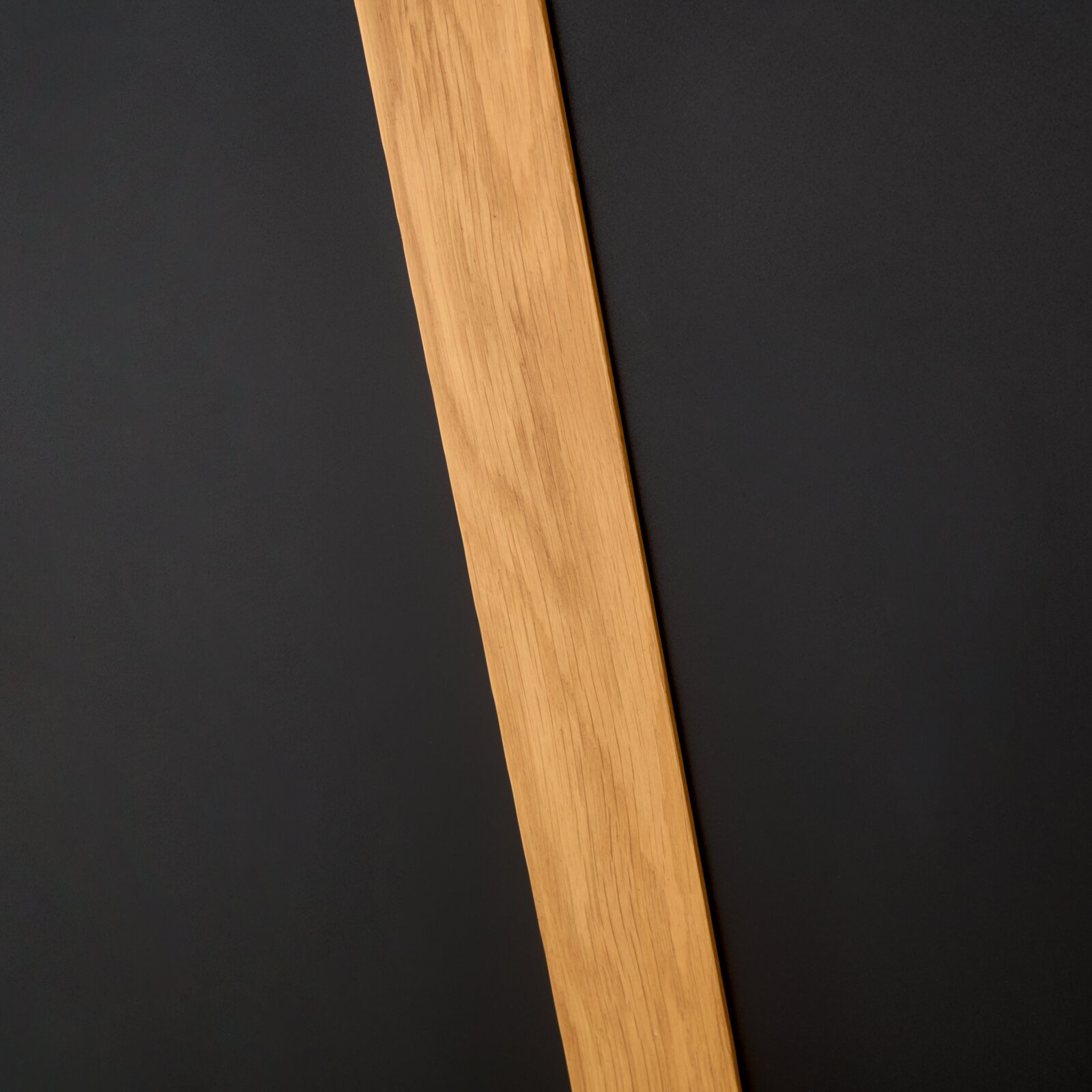 Nahaufnahme eines Esstischbeins aus Holz vor einem dunklen Hintergrund, diagonale Perspektive