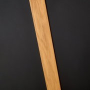 Nahaufnahme eines Esstischbeins aus Holz vor einem dunklen Hintergrund, diagonale Perspektive