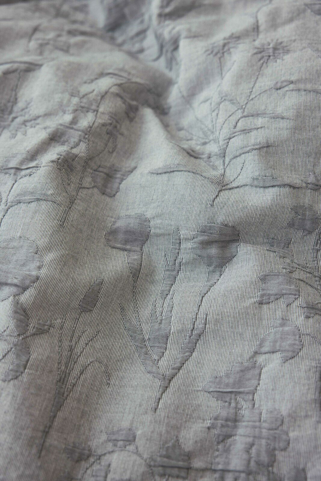 Nahaufnahme einer Bettwäsche mit floralen Mustern in Grau.