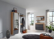 Modernes Flur-Set in Eiche-Optik mit anthrazitfarbenen Fronten: hoher Garderobenschrank mit Spiegeltür, Wandgarderobe mit Ablage und Haken sowie schwebende Kommode mit Spiegel, gezeigt in schräger Frontansicht im hellen Raum.