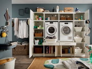 Vorderansicht eines modernen Hauswirtschaftsraums mit geöffneten Schränken, die Waschmaschine, Trockner und verschiedene Haushaltsgegenstände zeigen.