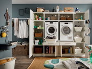Vorderansicht eines modernen Hauswirtschaftsraums mit geöffneten Schränken, die Waschmaschine, Trockner und verschiedene Haushaltsgegenstände zeigen.