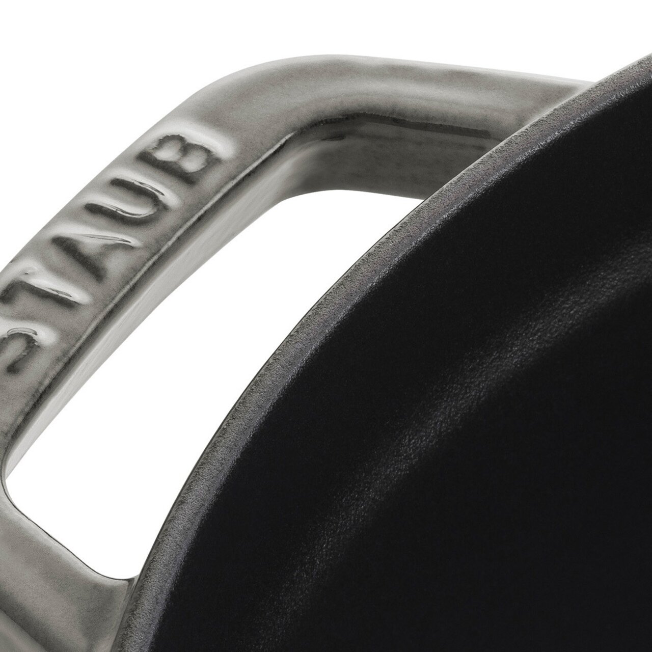Nahaufnahme eines Griffs eines runden Bräters Cocotte 28cm von oben, mit der Aufschrift 'STAUB'.