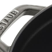 Nahaufnahme eines Griffs eines runden Bräters Cocotte 28cm von oben, mit der Aufschrift 'STAUB'.
