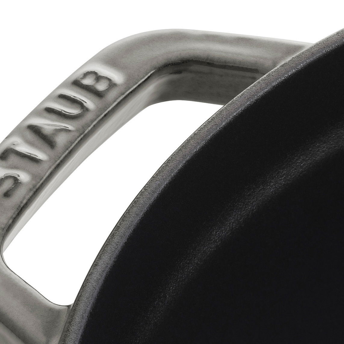 Nahaufnahme eines Griffs eines runden Bräters Cocotte 28cm von oben, mit der Aufschrift 'STAUB'.