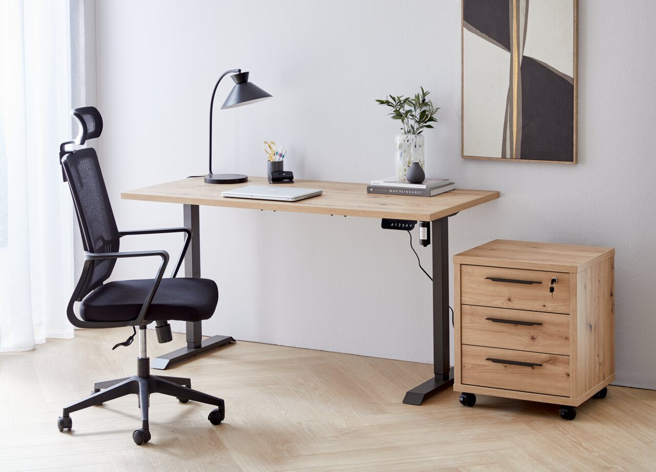 Moderner Arbeitsplatz mit höhenverstellbarer E-Tischplatte aus Holz, schwarzem Bürostuhl und Rollcontainer, seitliche Perspektive.