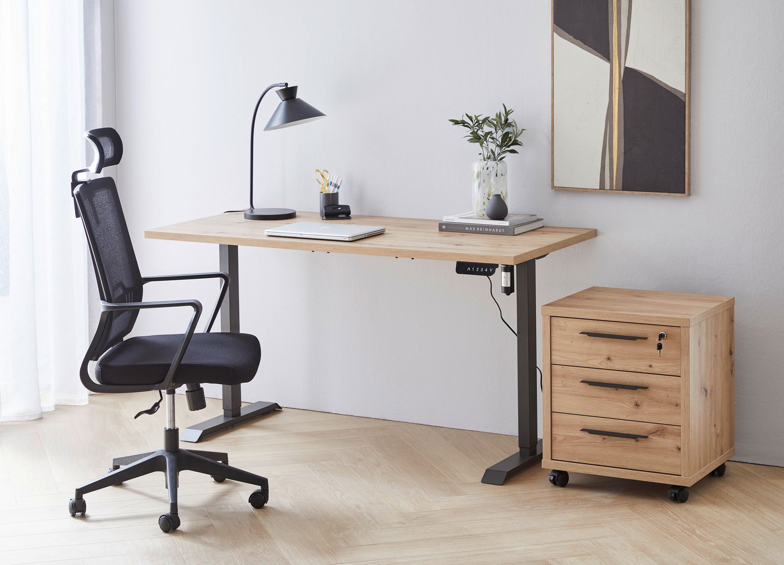 Moderner Arbeitsplatz mit höhenverstellbarer E-Tischplatte aus Holz, schwarzem Bürostuhl und Rollcontainer, seitliche Perspektive.