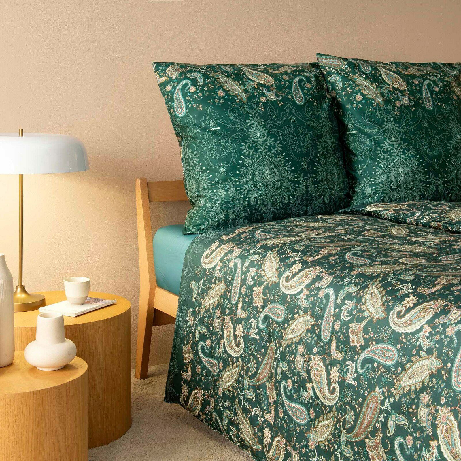 Bettwäsche-Set in Grün mit Paisley-Muster, auf einem Bett mit Holzkopfteil, seitliche Perspektive