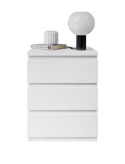 Weiße Nachtkommode mit drei Schubladen, darauf eine moderne Tischlampe, ein Buch und eine dekorative Vase, frontal betrachtet.