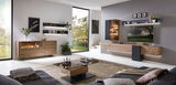 Modernes Wohnzimmer mit einem eleganten Sideboard aus Holz, das von der Seite betrachtet wird. Das Sideboard hat eine Glasvitrine und ist Teil einer stilvollen Einrichtung mit Wandregalen und einem großen Fenster mit Blick ins Grüne.