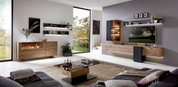 Een moderne woonkamer met een elegant houten dressoir, hier gezien vanaf de zijkant. Het dressoir heeft een glazen vitrinekast en maakt deel uit van een stijlvolle inrichting met wandplanken en een groot raam met uitzicht op het groen.